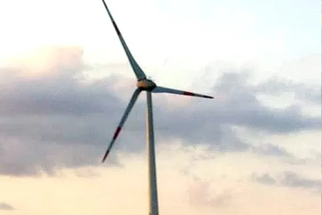 Wind turbine with a damaged blade against a cloudy sunset sky with soft pastel colors.