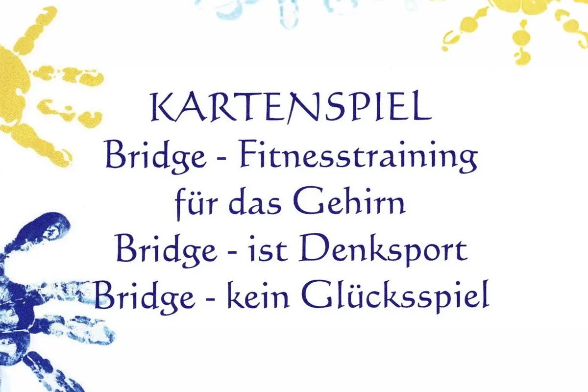 German sign: 'KARTENSPIEL Bridge - Fitnesstraining für das Gehirn Bridge - ist Denksport Bridge - kein Glücksspiel' with blue and yellow handprints around it.
