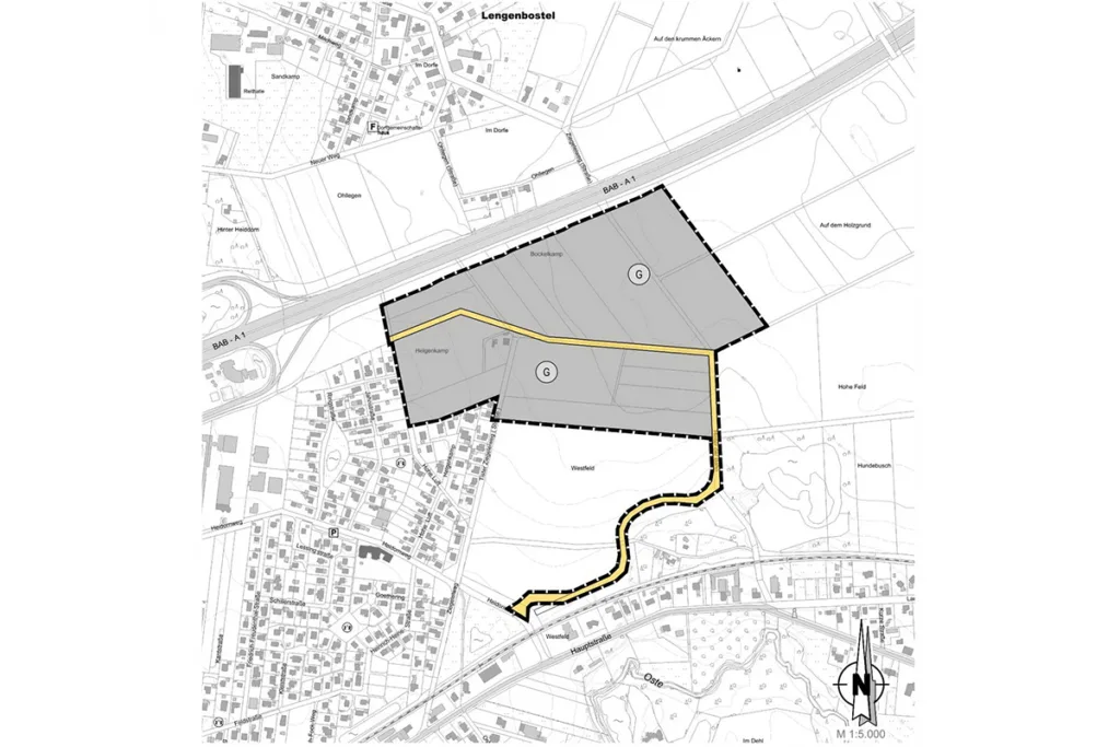 Site plan with two grey parcels enclosed by a dashed black boundary; a yellow access road winds through the area amid surrounding streets and buildings; north arrow visible at bottom-right.